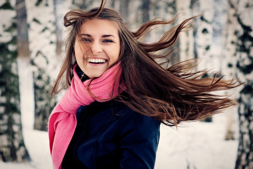 Junge Frau im Winter draußen mit wehenden Haaren