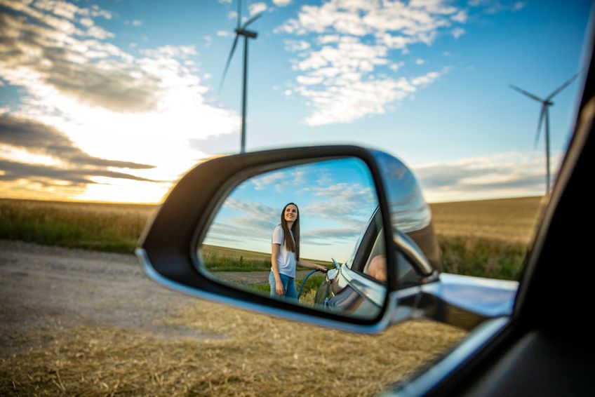 Junge Frau lädt Elektroauto mit Ökostrom