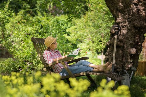 Frau auf Liegestuhl im Garten entspannt sich