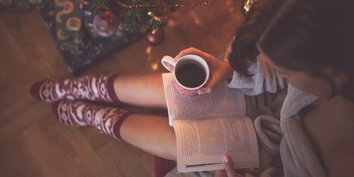 Eine Frau liest in weihnachtlicher Atmosphäre ein Buch.