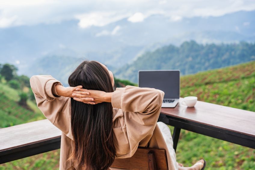 Frau mit Laptop entspannt sich vor Bergpanorama