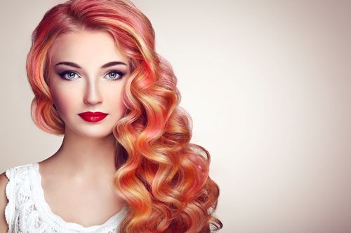 Frau mit mehrfarbig rot gefärbtem, lockigen Haar