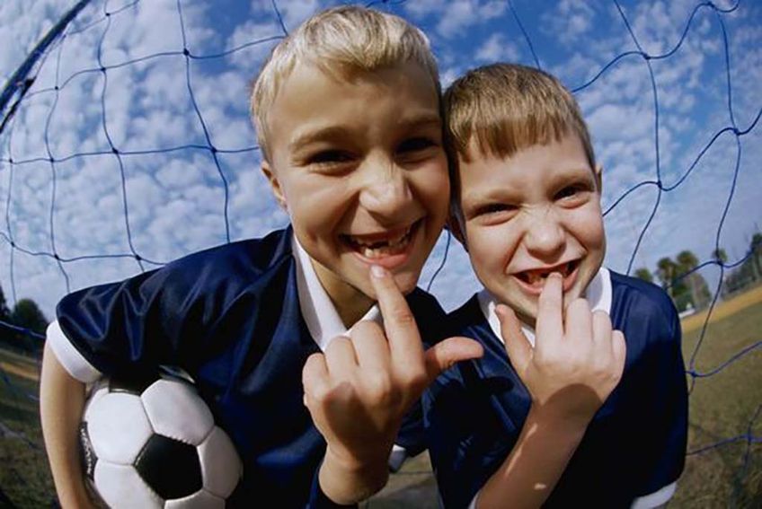 Kinder mit Zahnlücken beim Fußballspielen