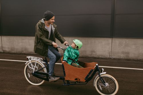 Vater transportiert Kind mit Lastenrad