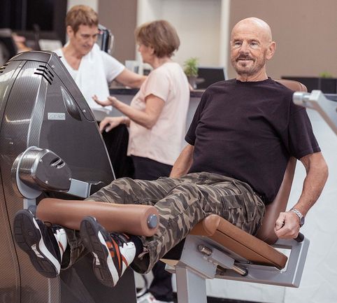 Mann in Fitnessstudio auf Trainingsgerät für die Beine.